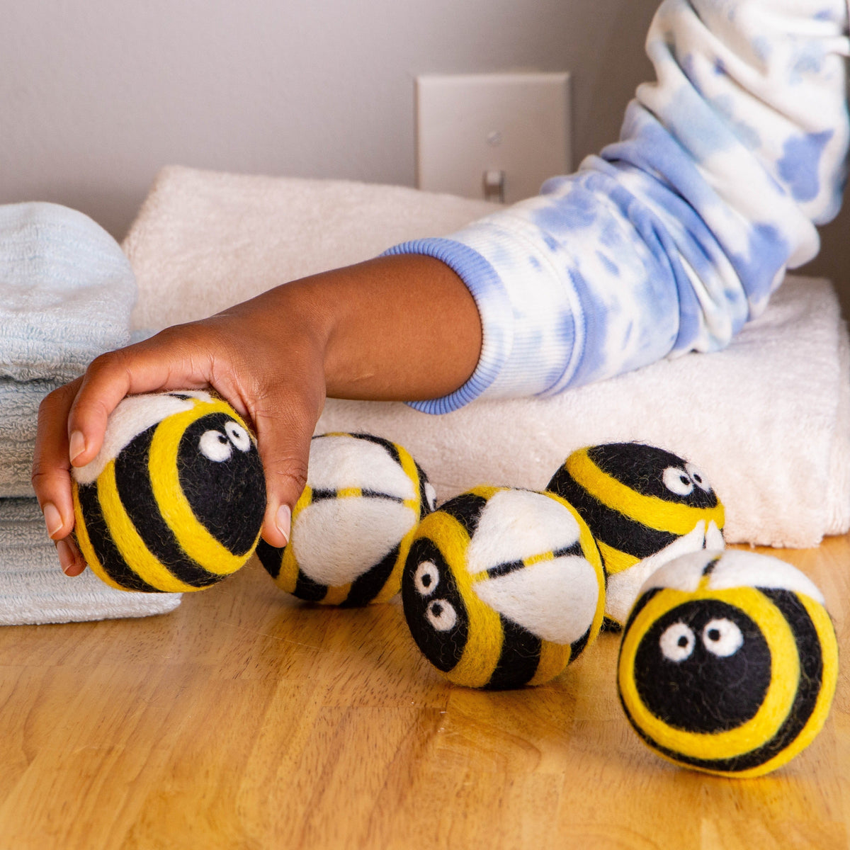 Plush bee dryer balls scattered, yellow-and-black striped round plush with cute faces