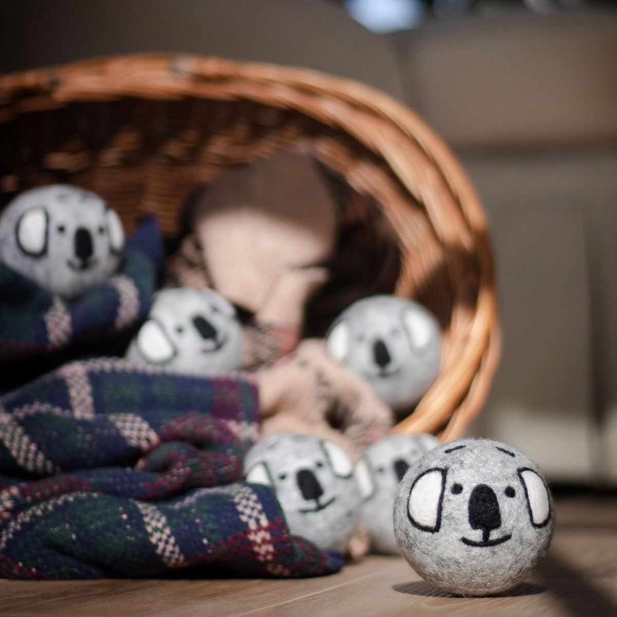 Set of small gray koala plush balls resting in a wicker basket with blankets