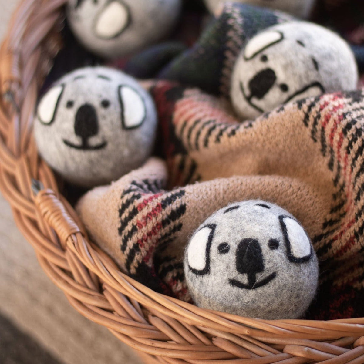 Gray koala plush balls on a plaid blanket inside a wicker basket