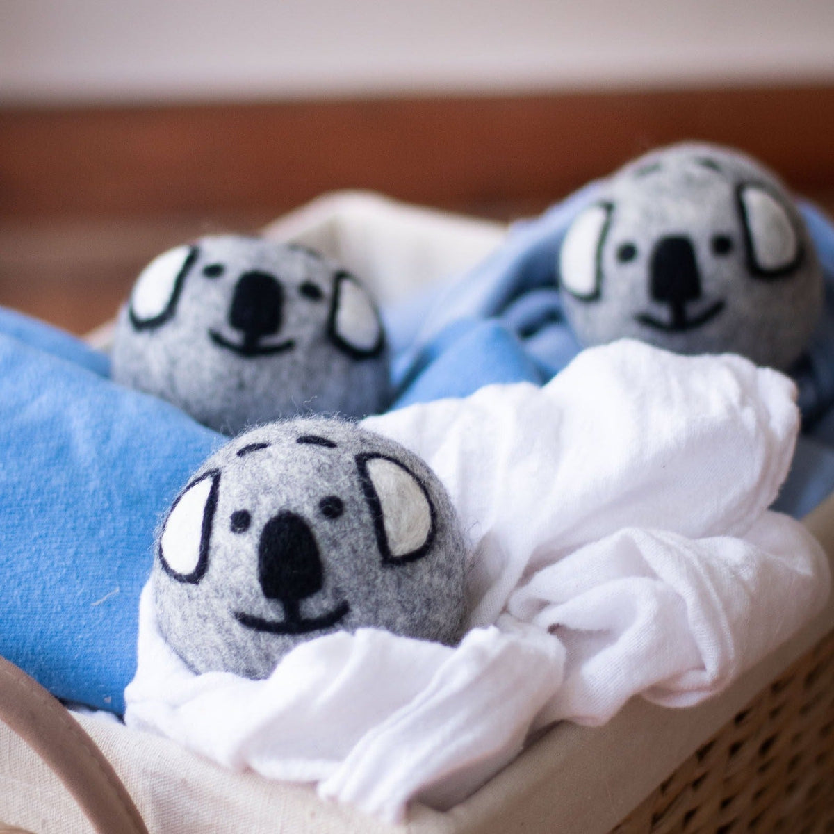 Three gray koala plush balls nestled in a white and blue blanket