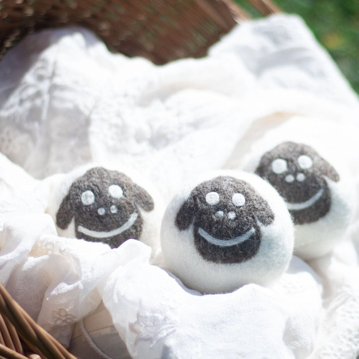 Felt wool sheep dryer balls on bedding, three smiling faces visible