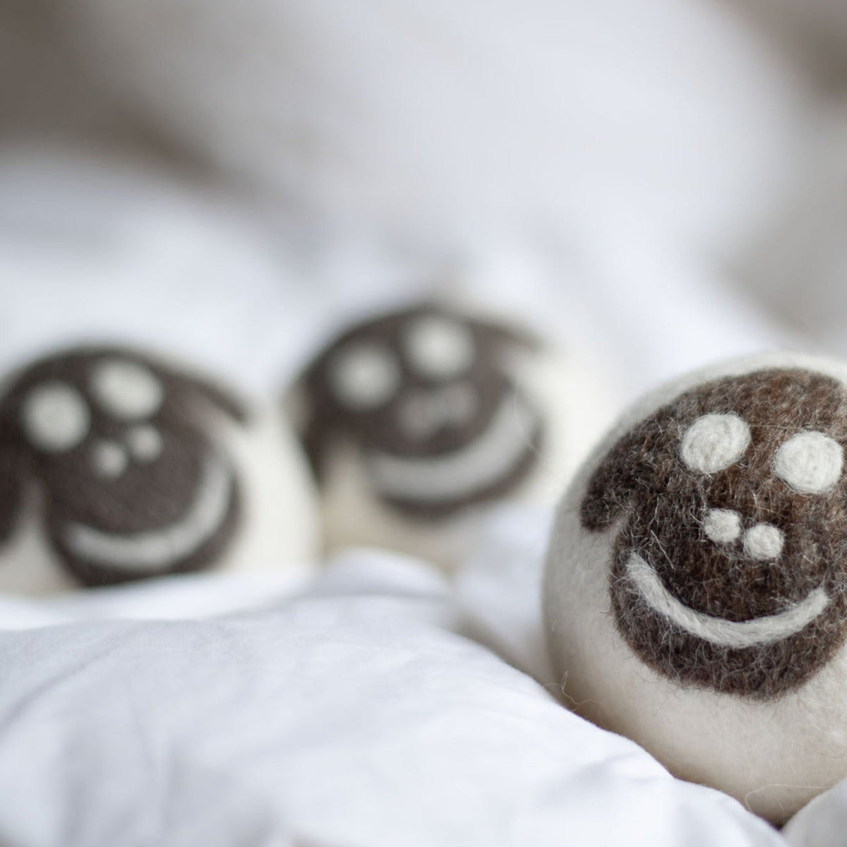Close-up of felt wool sheep dryer balls with smiling faces and white paw dots