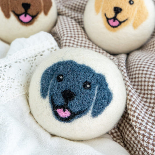 Blue felt dog-face button on white lace and plaid fabric, partial others visible.