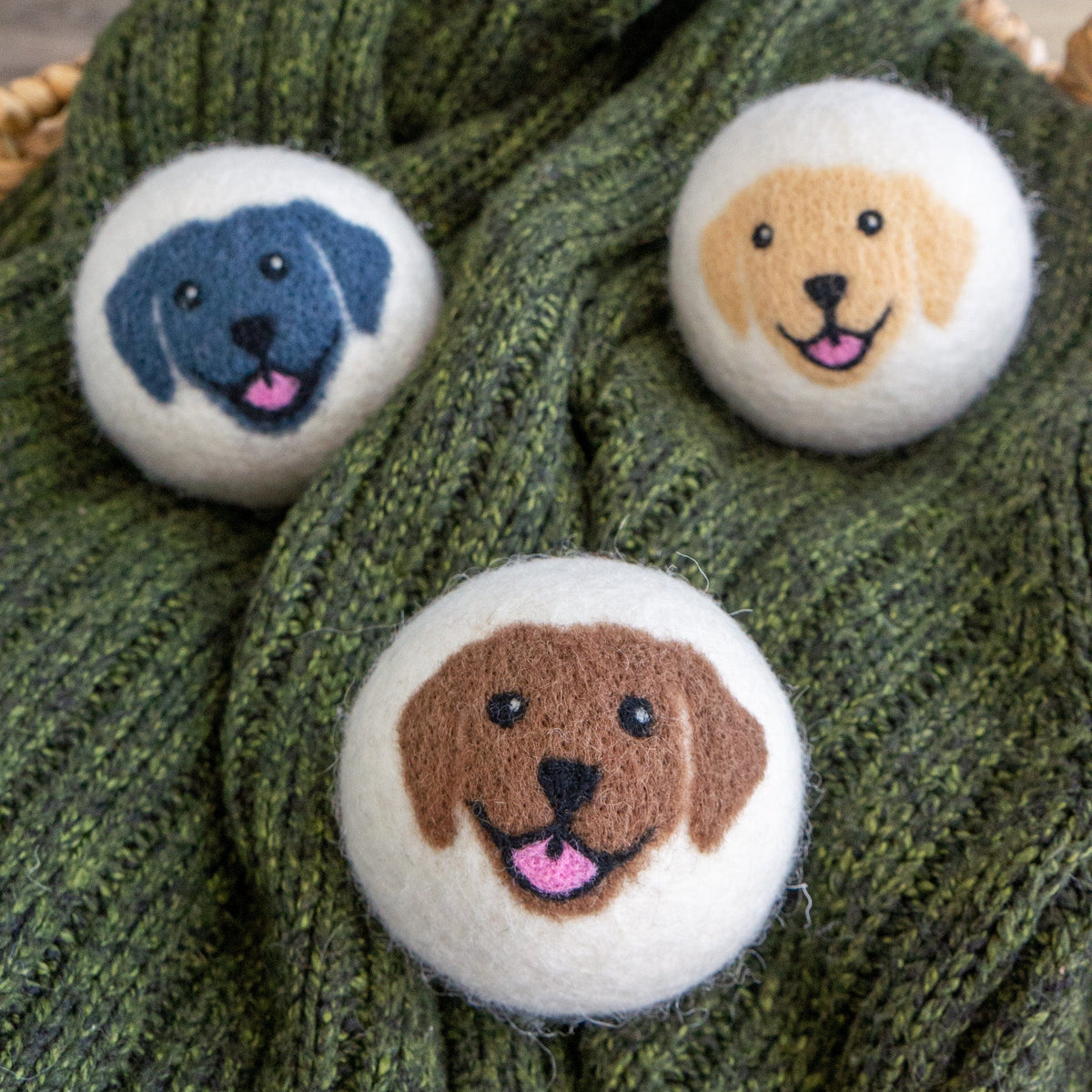 Three felt dog-face buttons on green knit fabric, close-up.