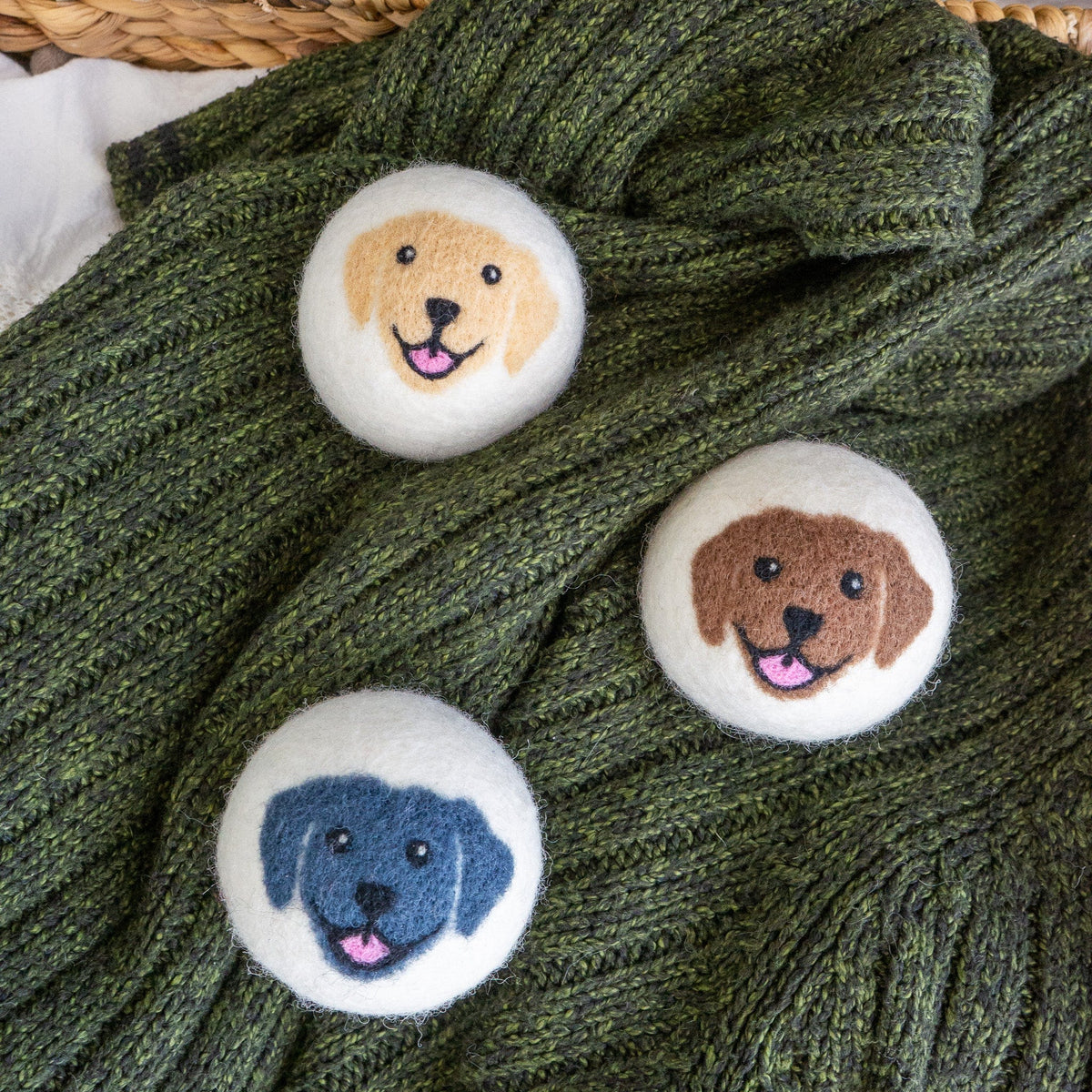 Four felt dog-face buttons scattered on green knit sweater fabric.