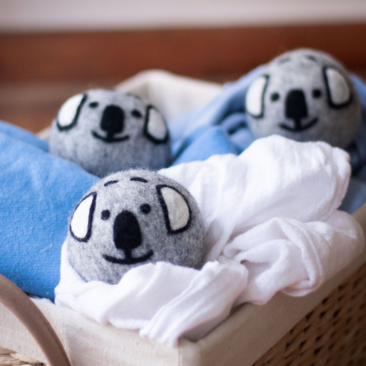 Gray koala dryer balls on a bed with white and blue bedding