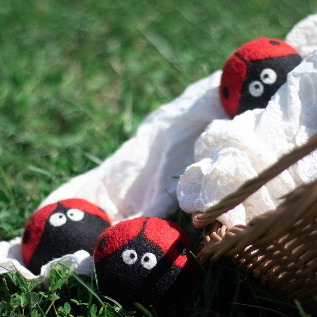 Plush ladybug trio nestled in white fabric with three red-and-black felt bugs