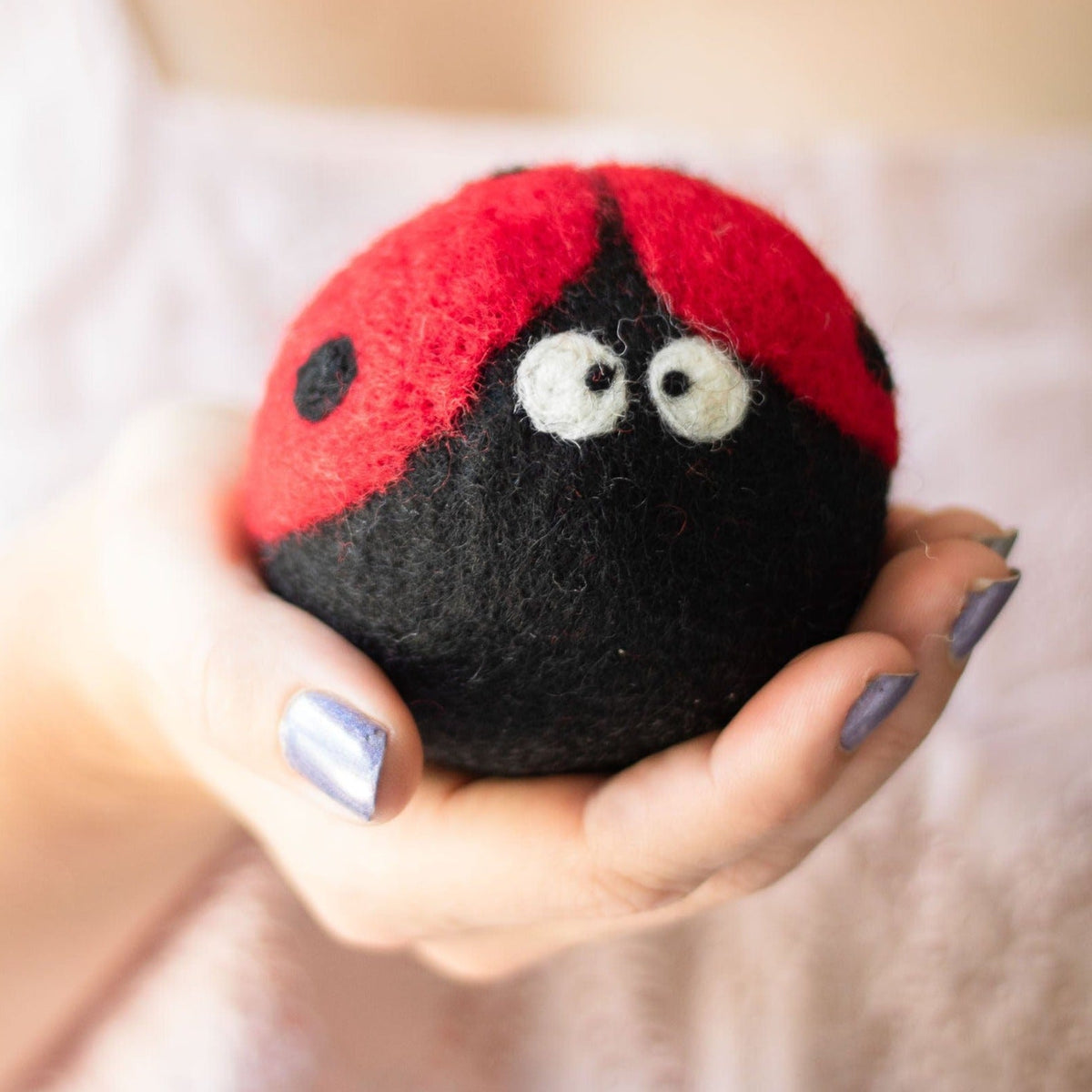 Handheld plush ladybug with red-and-black felt body and stitched white eyes