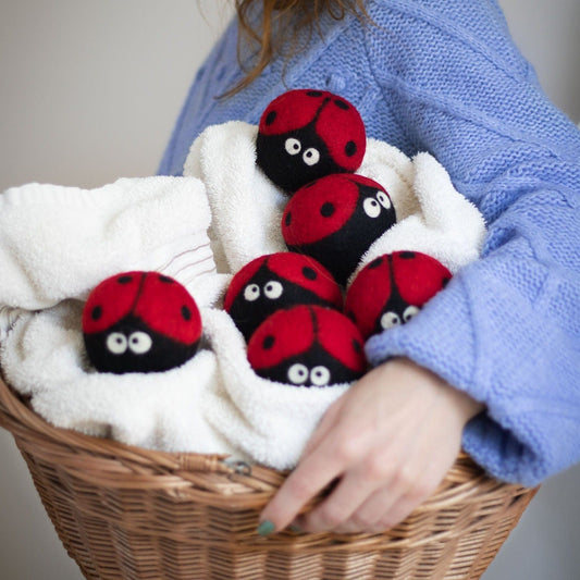 Plush ladybug dryer balls nestled in a laundry basket, red and black with eyes