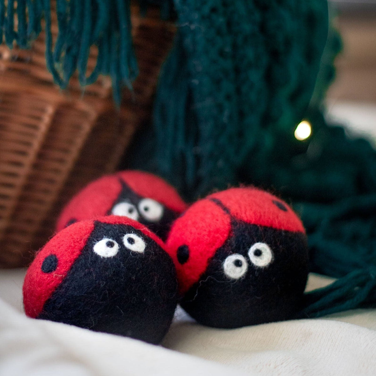 Plush ladybug dryer balls resting on a cushion, red tops and black faces with eyes