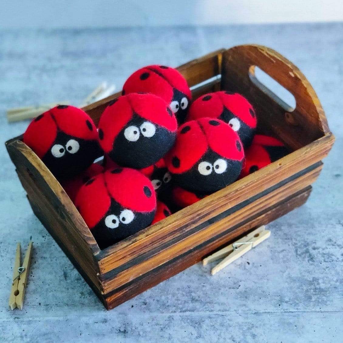 Plush ladybug dryer balls in a wooden crate, red and black with white eyes