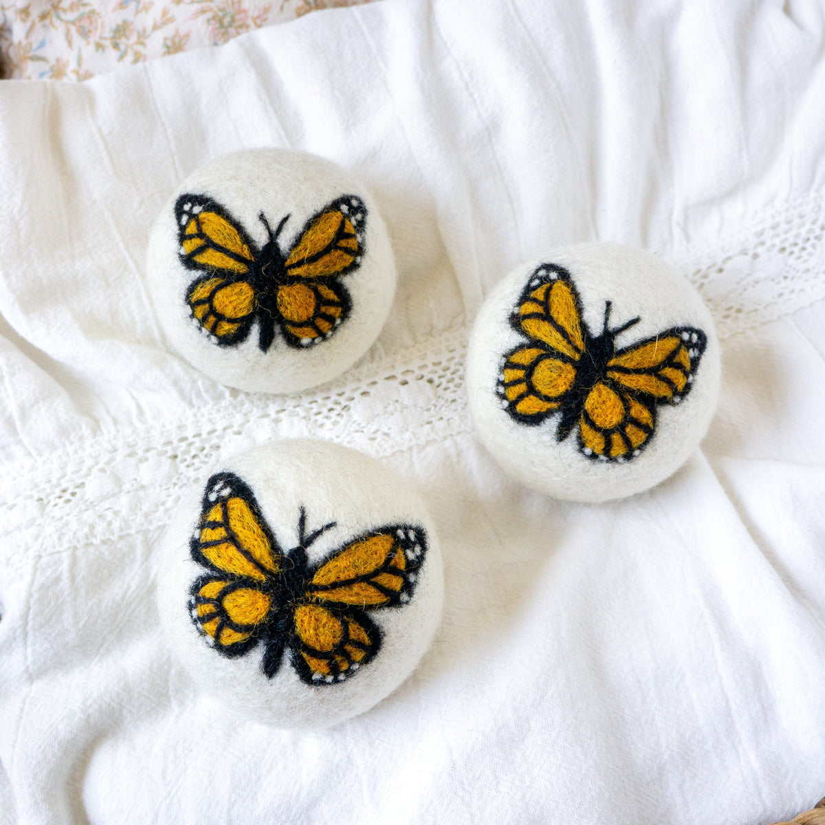 White fabric set with three Monarch butterfly embroidered felt balls