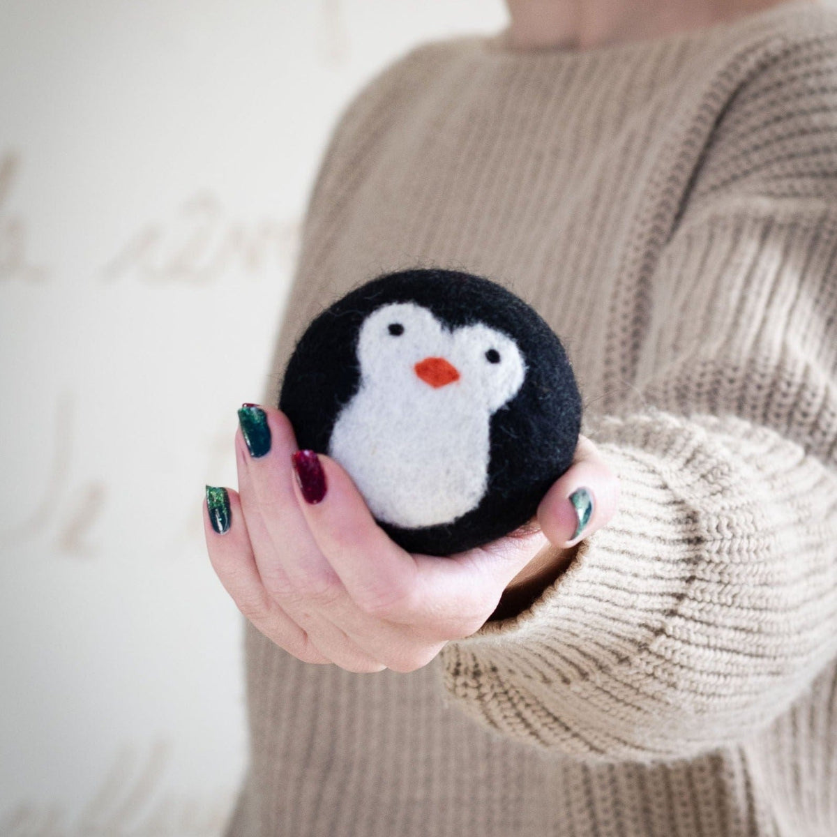 Black-and-white penguin plush held toward the camera with a cozy sweater