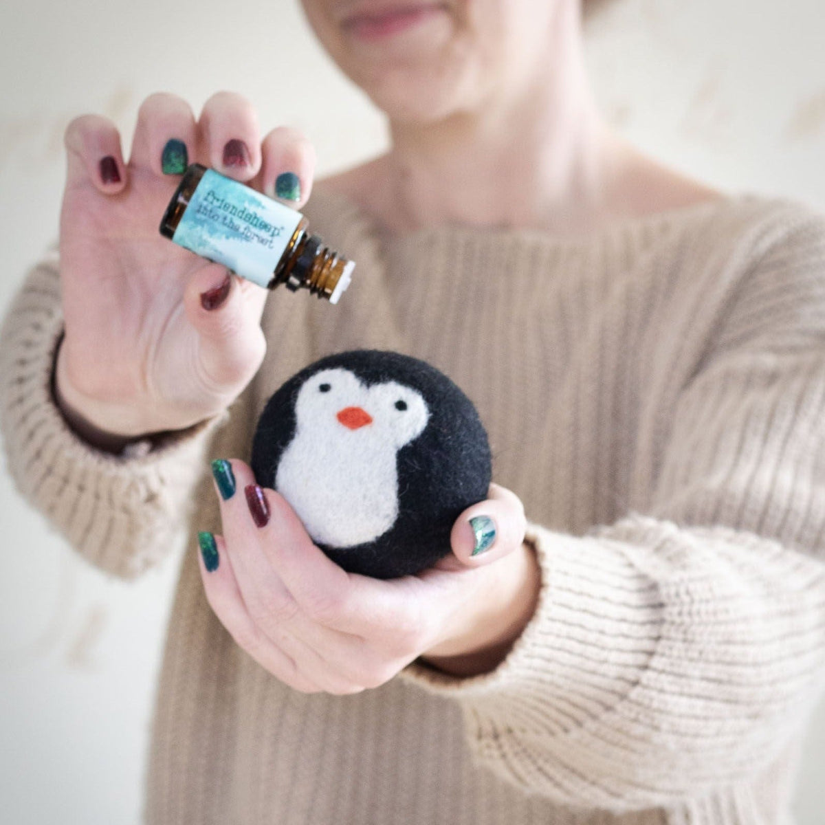 Small penguin plush held in hands, black-and-white with an orange beak
