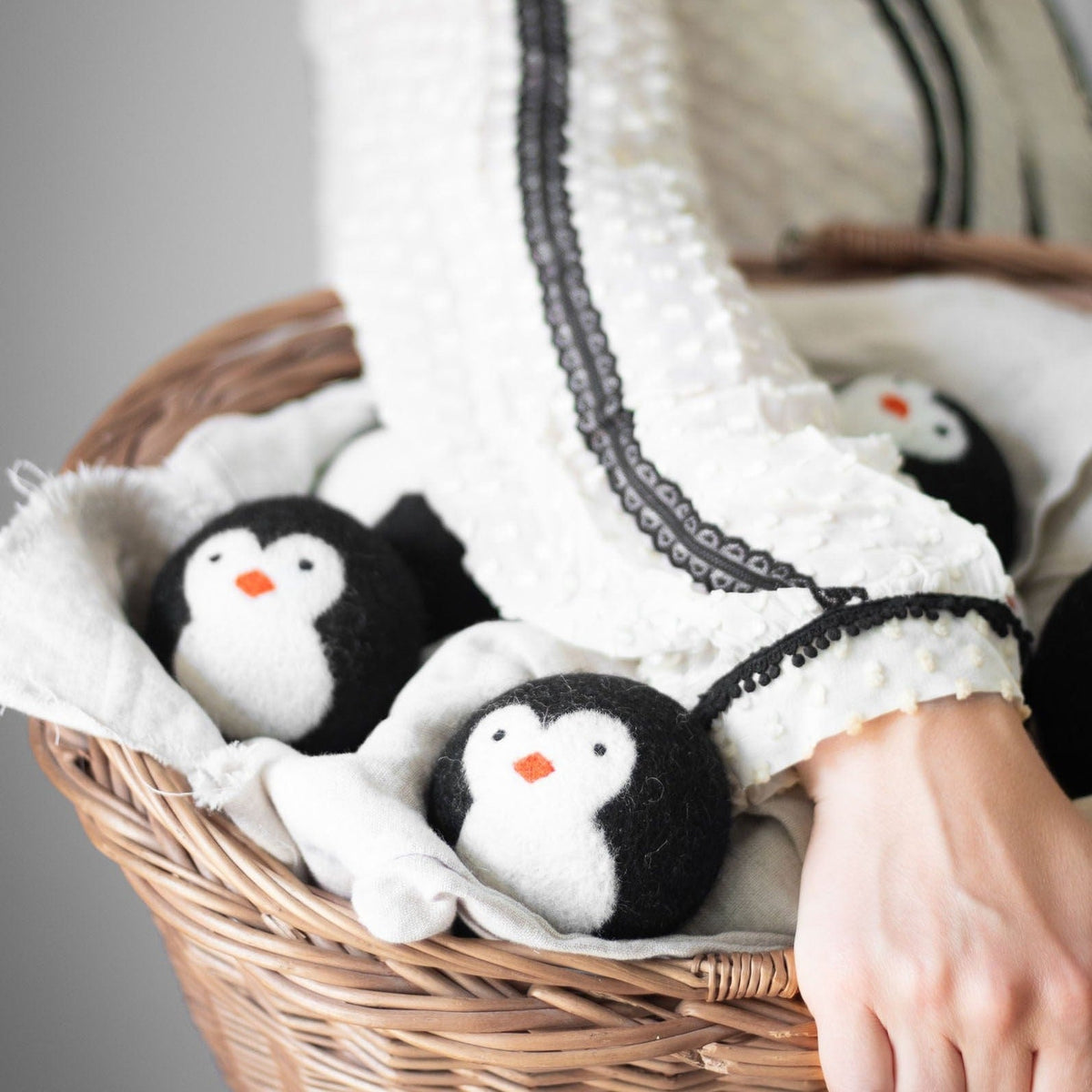 Three penguin plush toys in a woven basket lined with white fabric