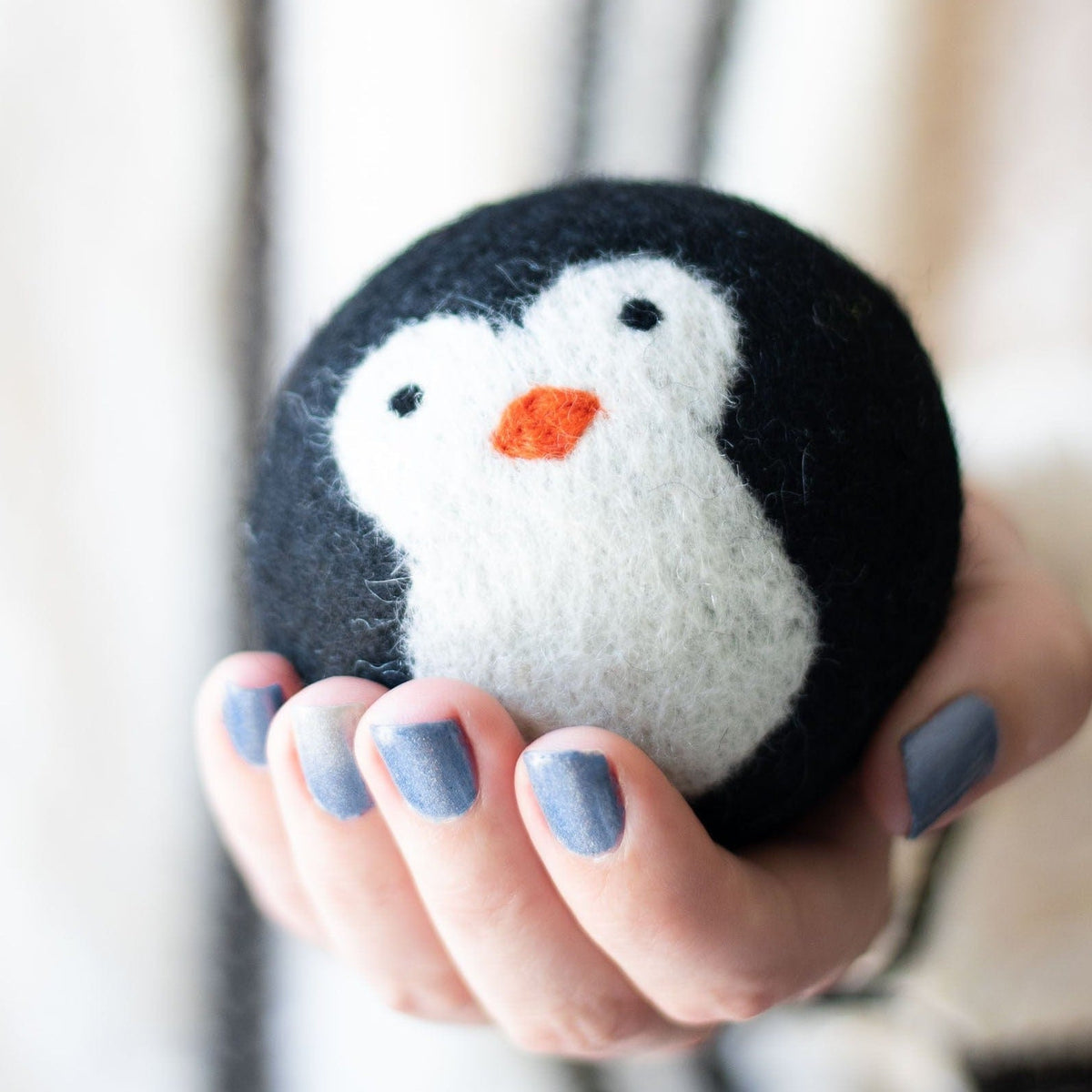 Black-and-white penguin plush with orange beak held in a hand