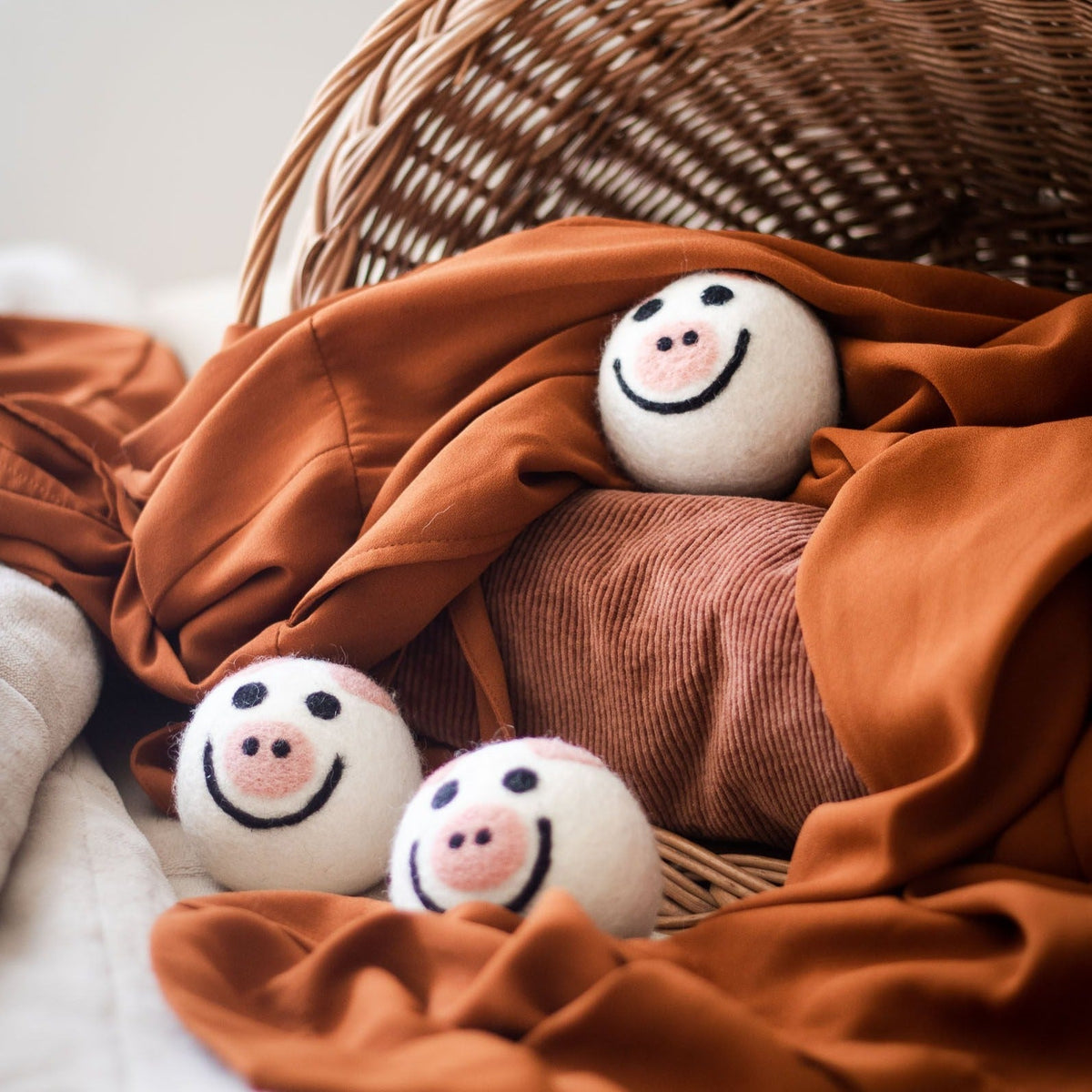 Pig plush toys nestled in a woven basket with orange and brown fabric