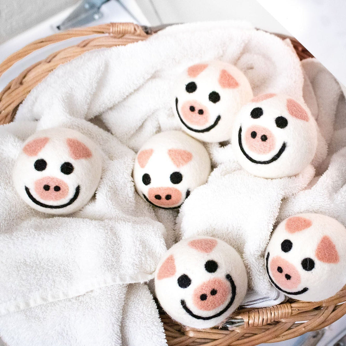 Pig plush toys on white fleece bedding inside a woven basket