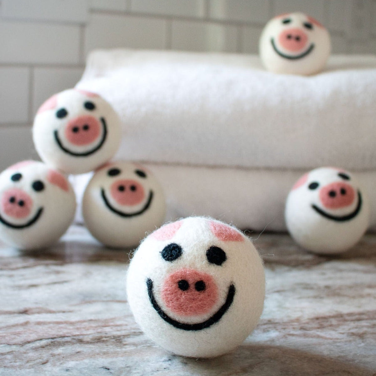 Five round pig plush toys with embroidered smiling faces on a sofa