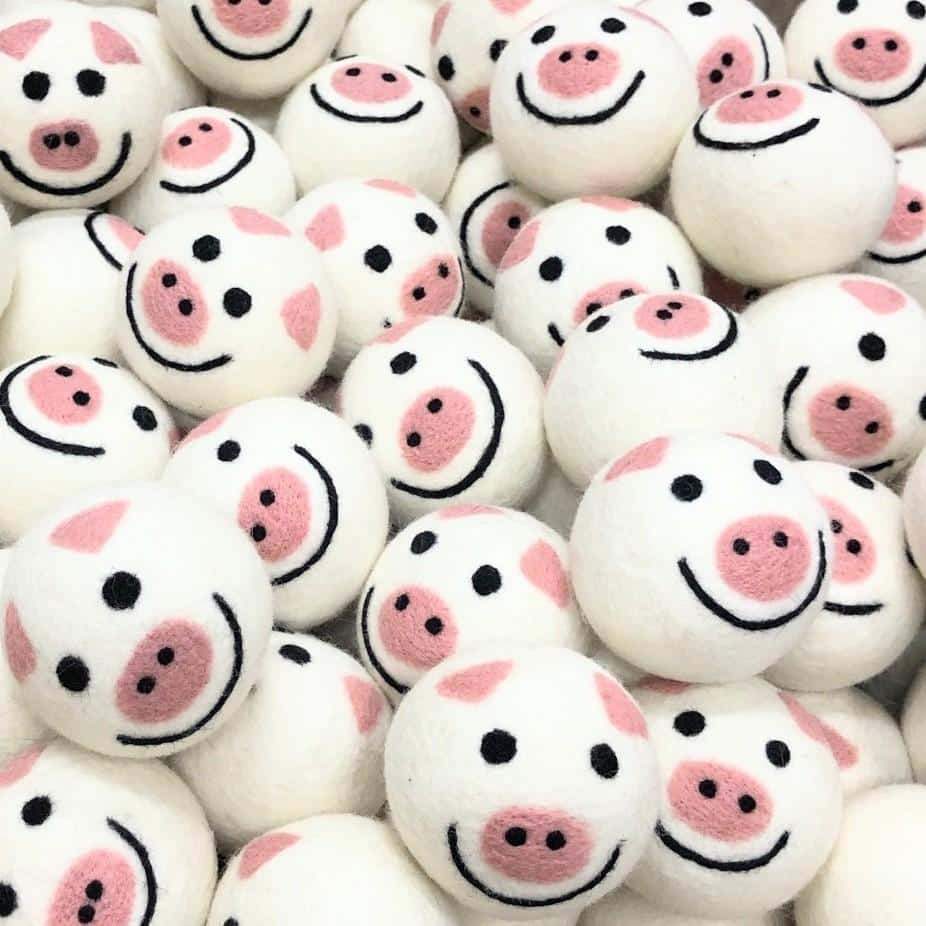 Assorted felt pig-shaped dryer balls with cute smiling faces