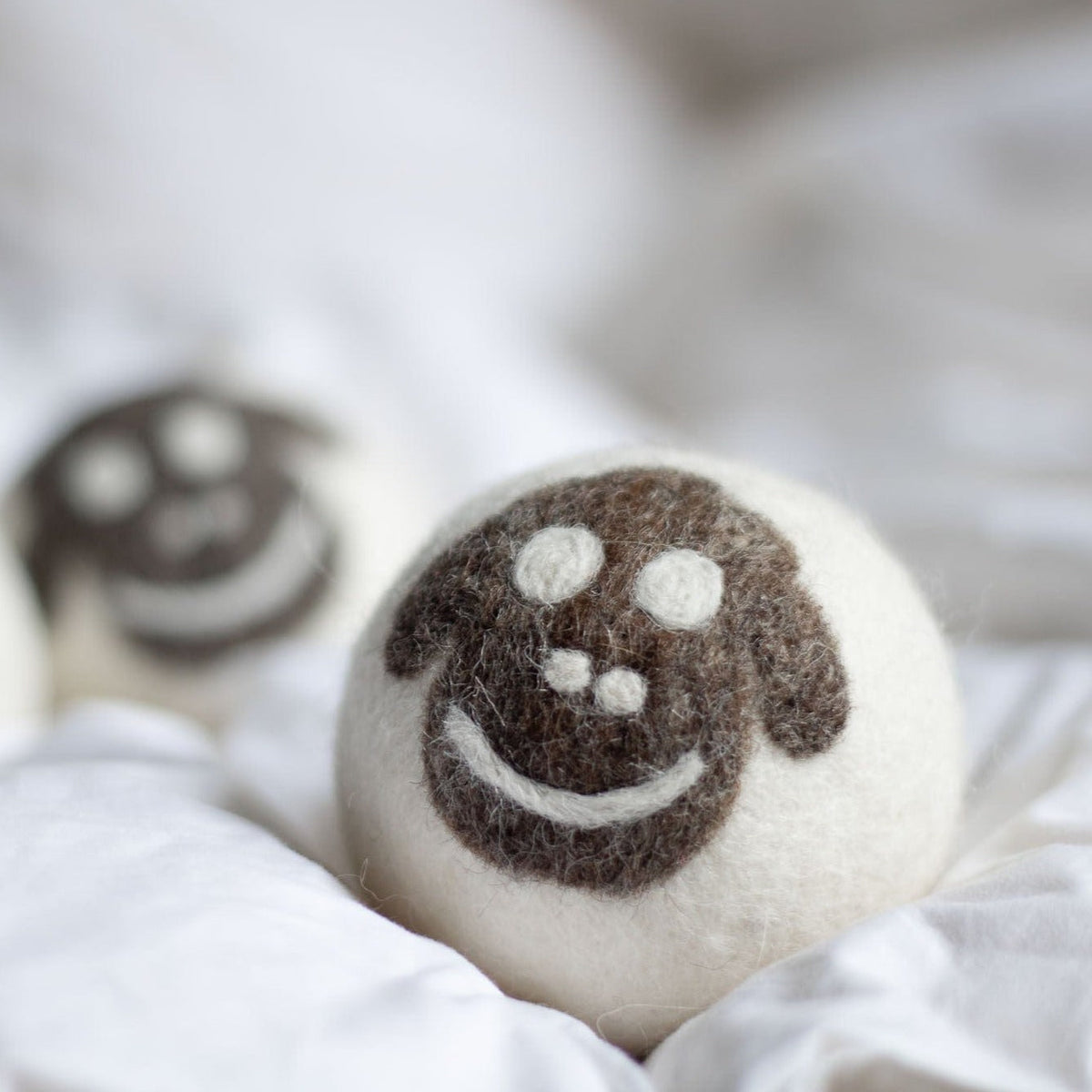 Felt sheep plush ball with embroidered smile, close-up