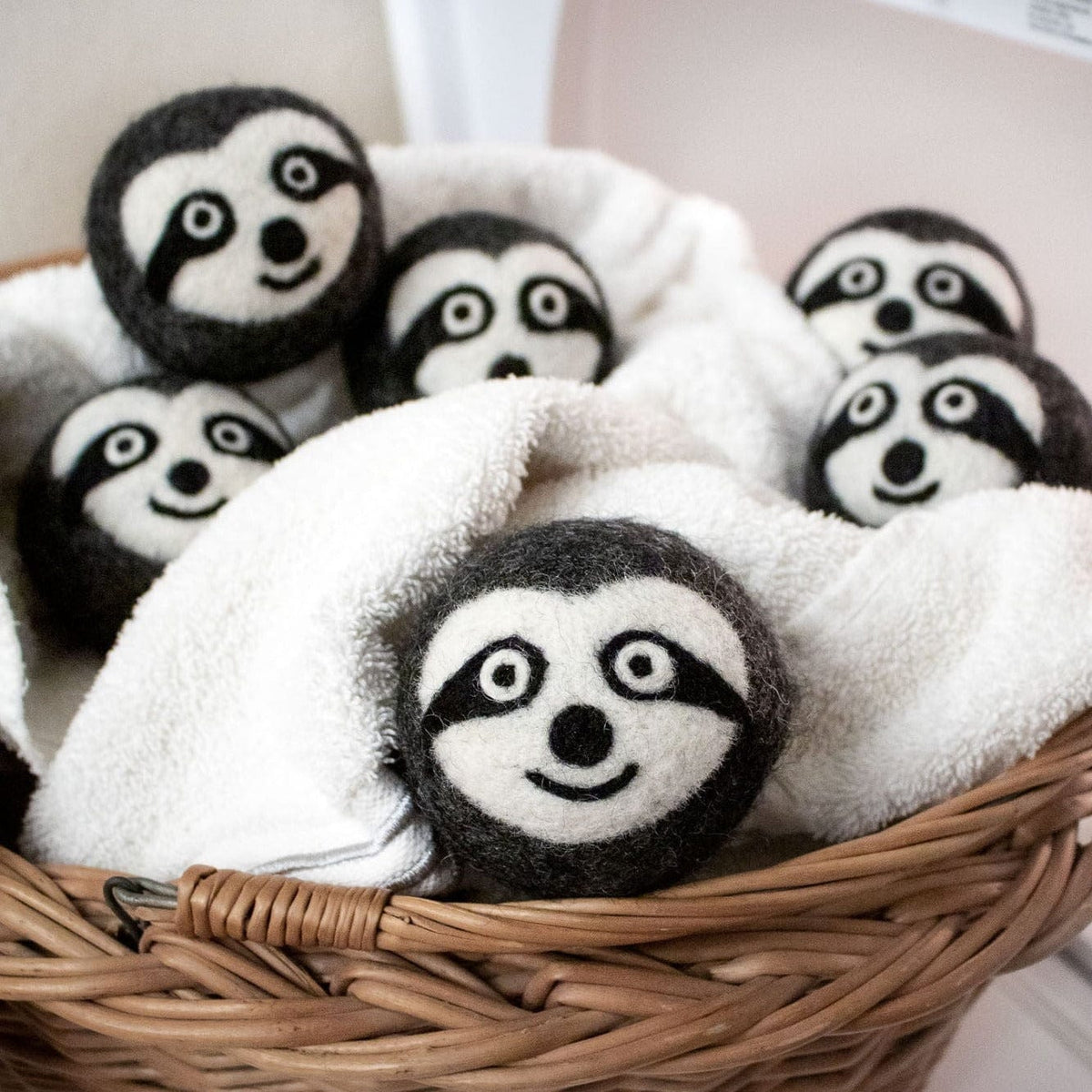 Basket filled with felt sloth dryer balls with embroidered faces