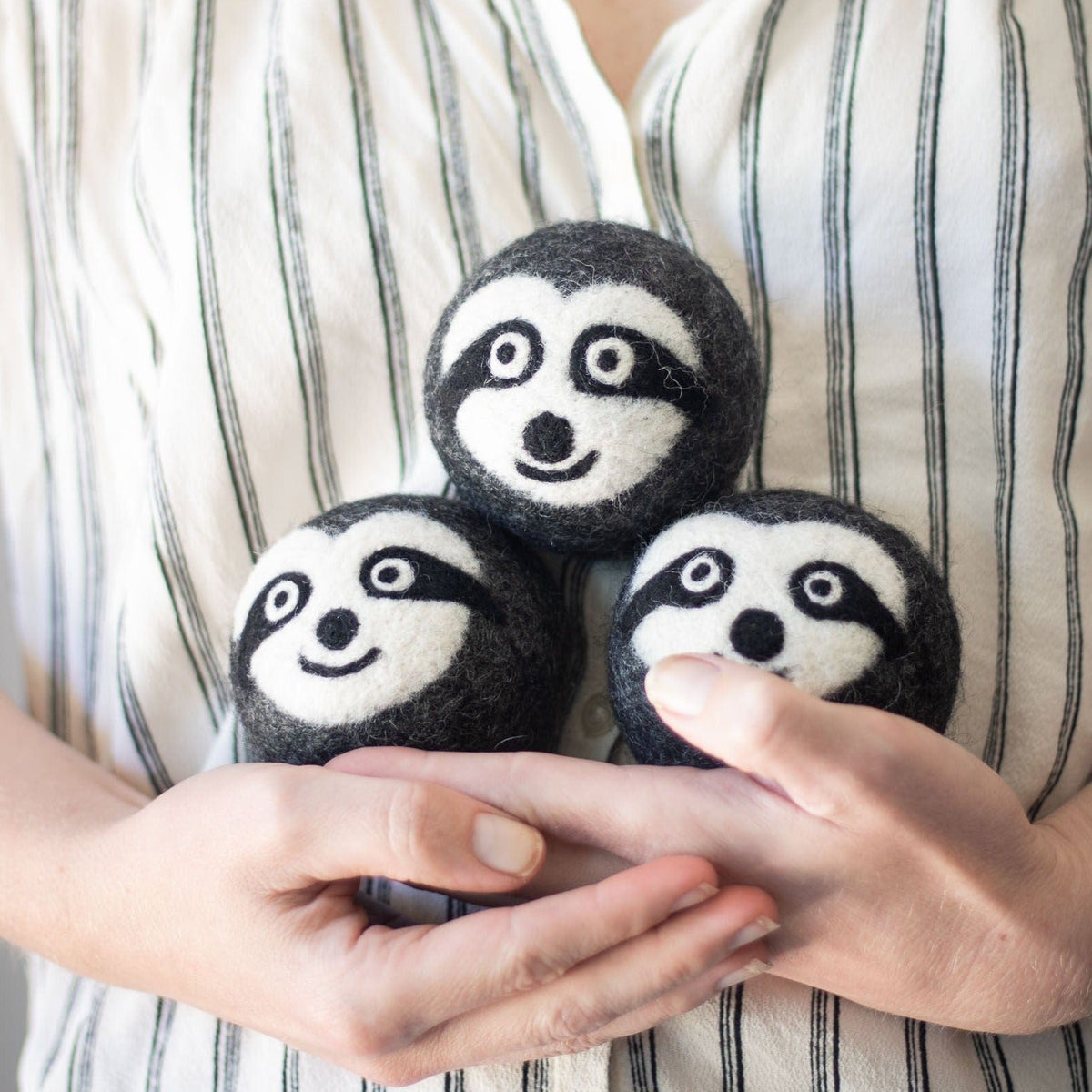 Felt sloth dryer balls with embroidered faces held in hands