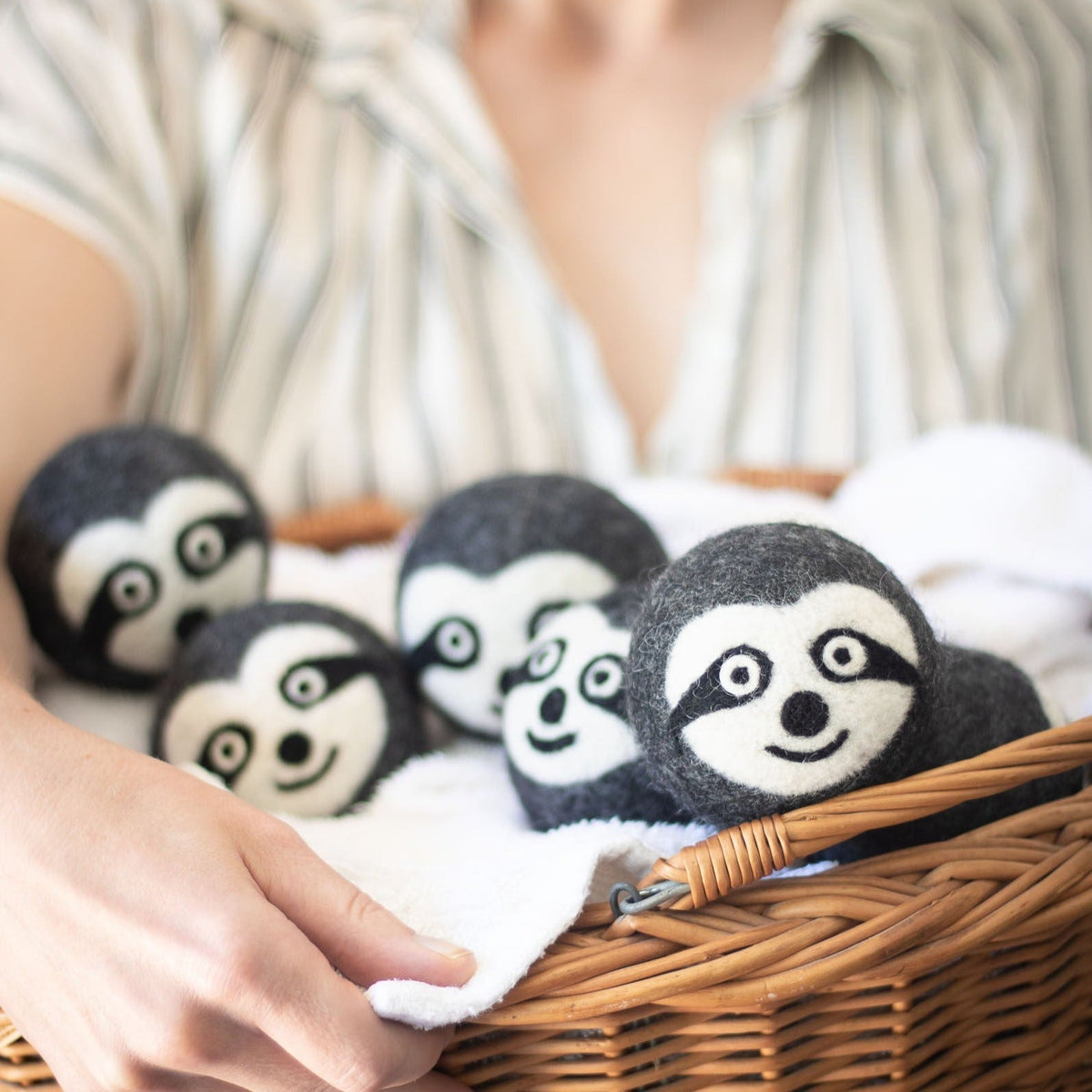 Set of felt sloth dryer balls with embroidered faces in a woven basket