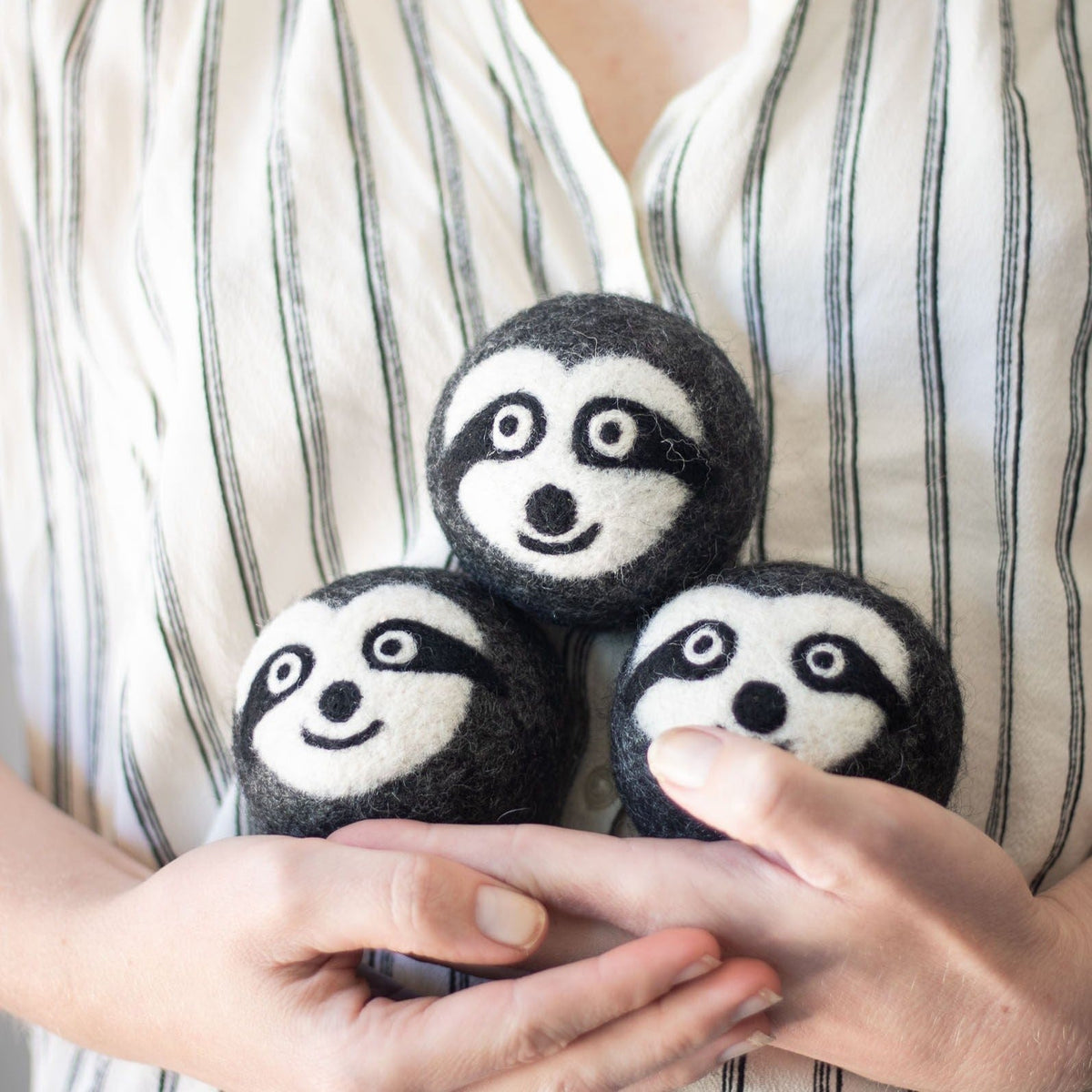 Set of three small felt sloth plush toys nestled in hands