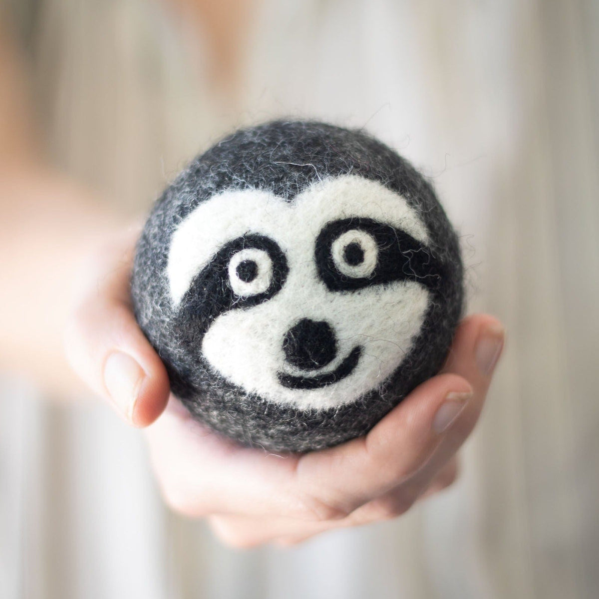 Single felt sloth plush ball with stitched black-and-white face
