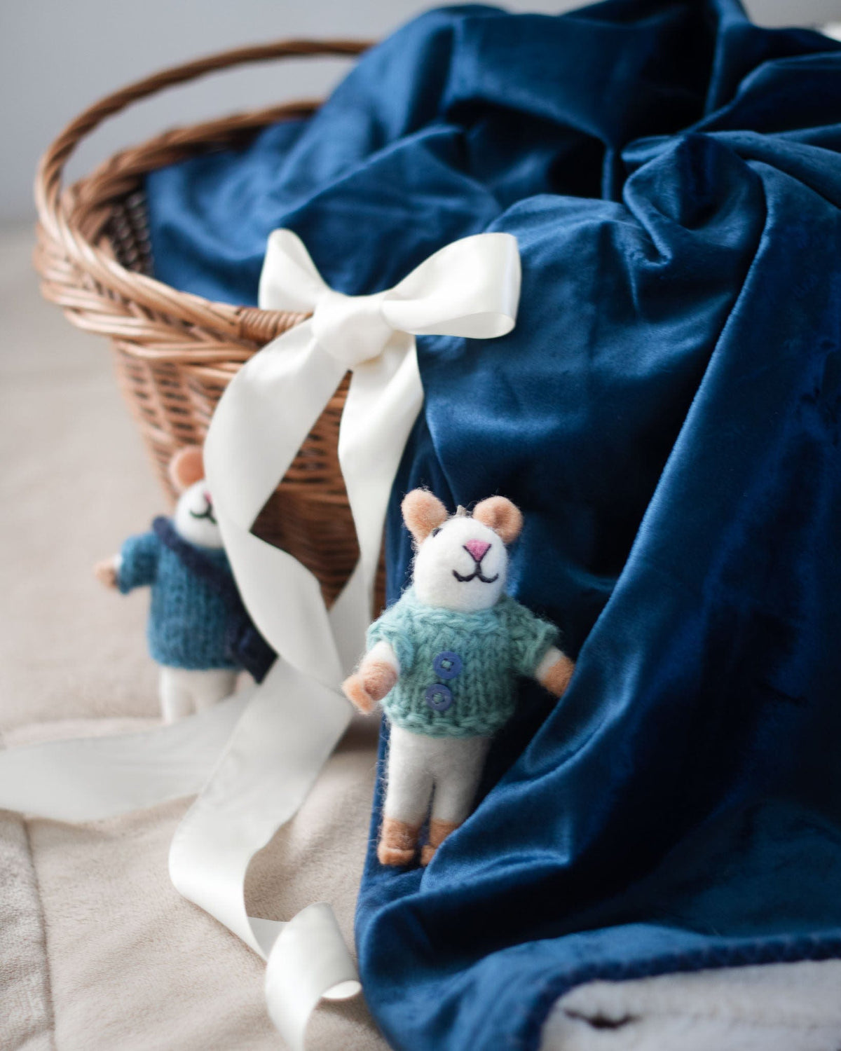 Mouse eco ornament in teal knit sweater tucked in gift basket with white bow.