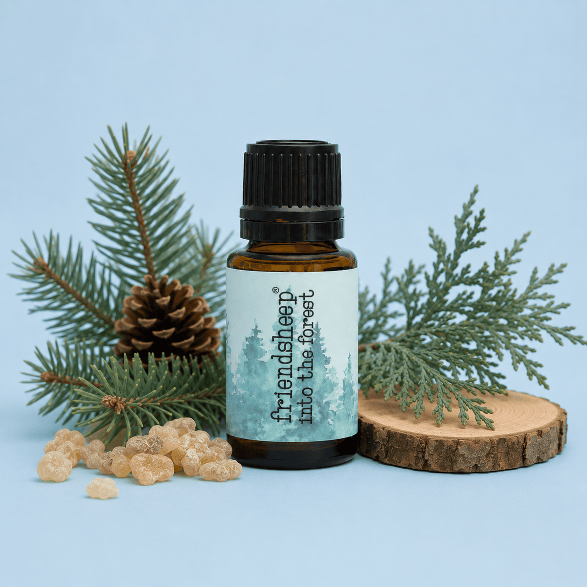 Amber essential oil blend bottle with black ribbed cap, teal label, on wood slice