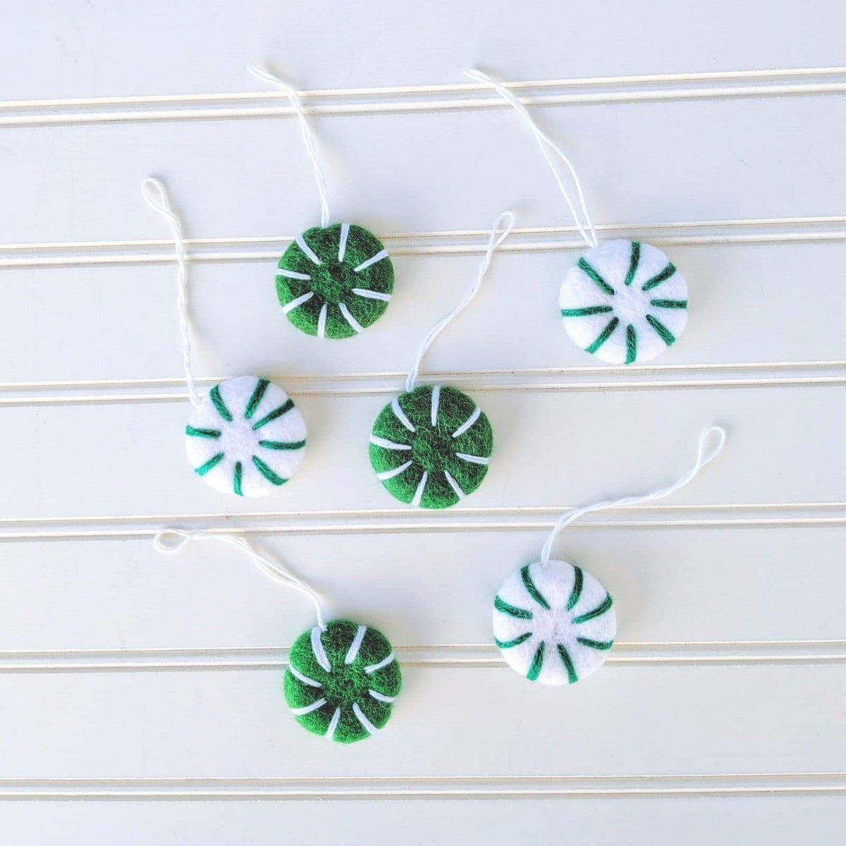 Assorted green-and-white felt peppermint swirl eco freshener ornaments on white cords