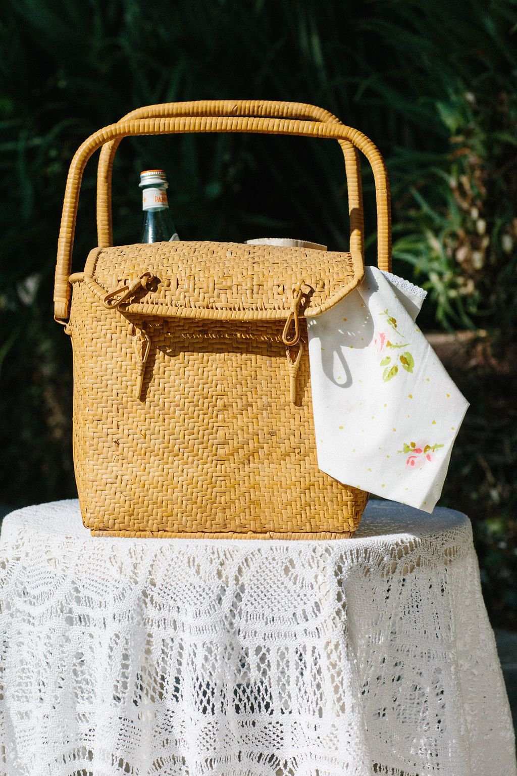 White floral face bandana with small roses, draped over wicker basket