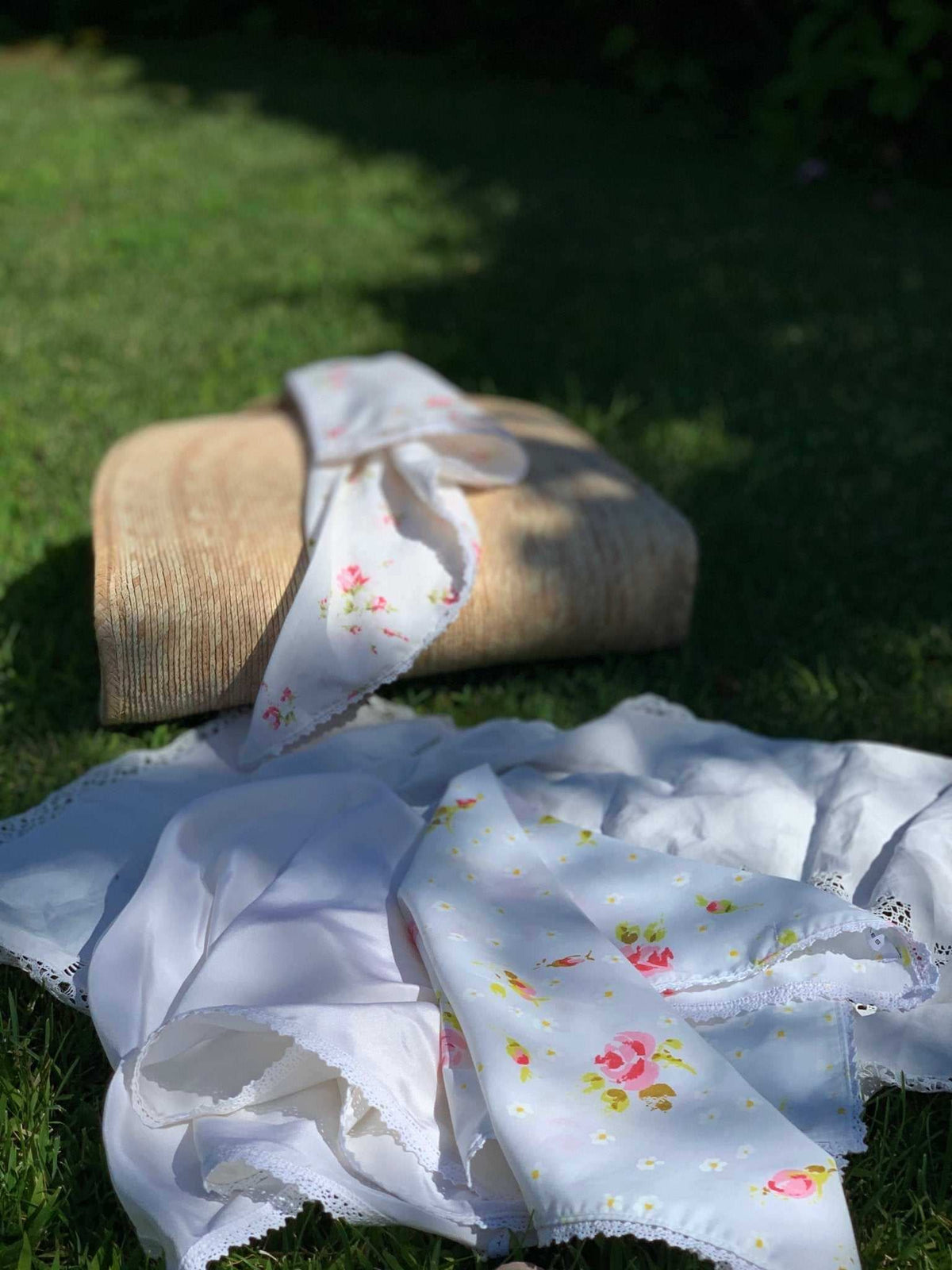 Light blue floral face bandana with small roses, folded on grass