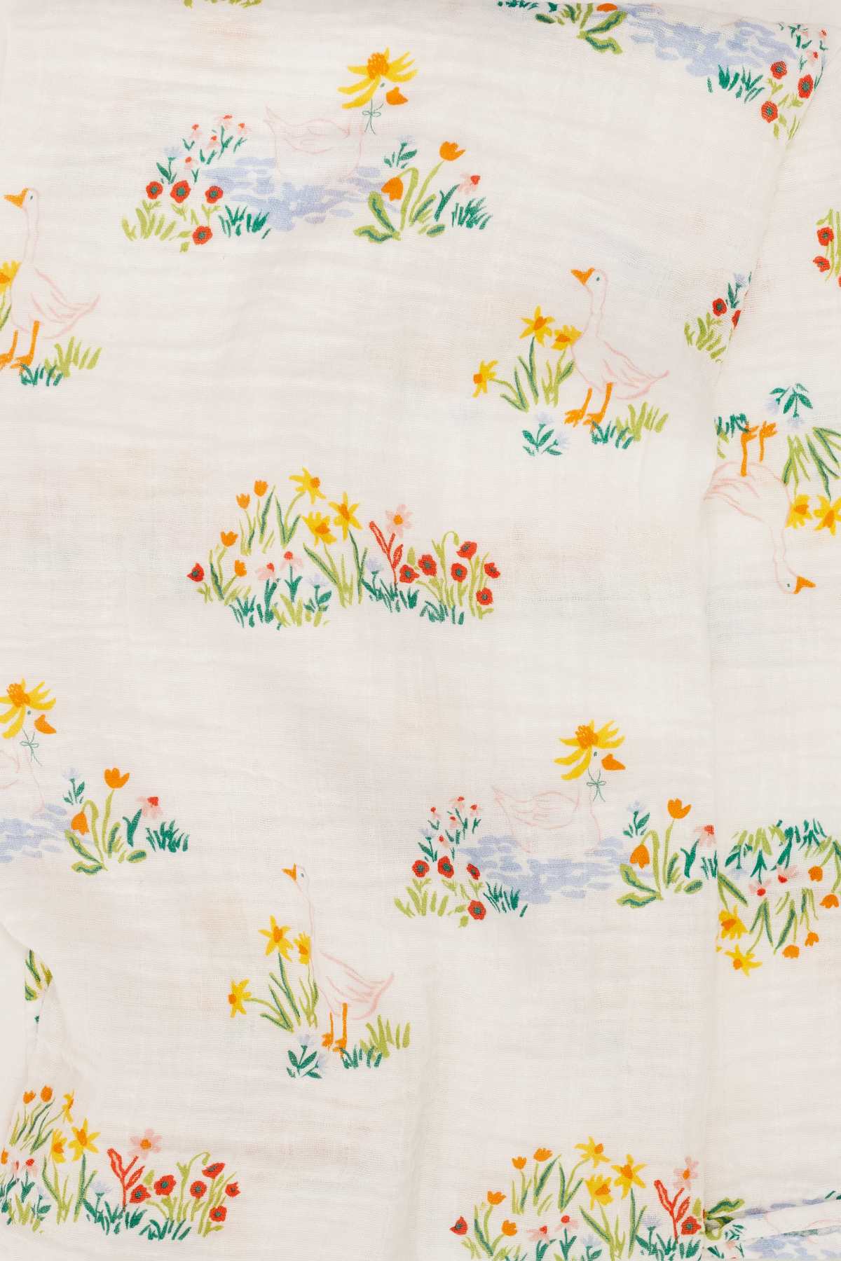 White swaddle fabric with colorful garden bird and flower pattern, close-up