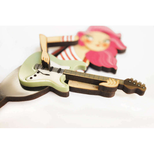 Enamel brooch detail: pale green electric bass with girl holding it, pink hair