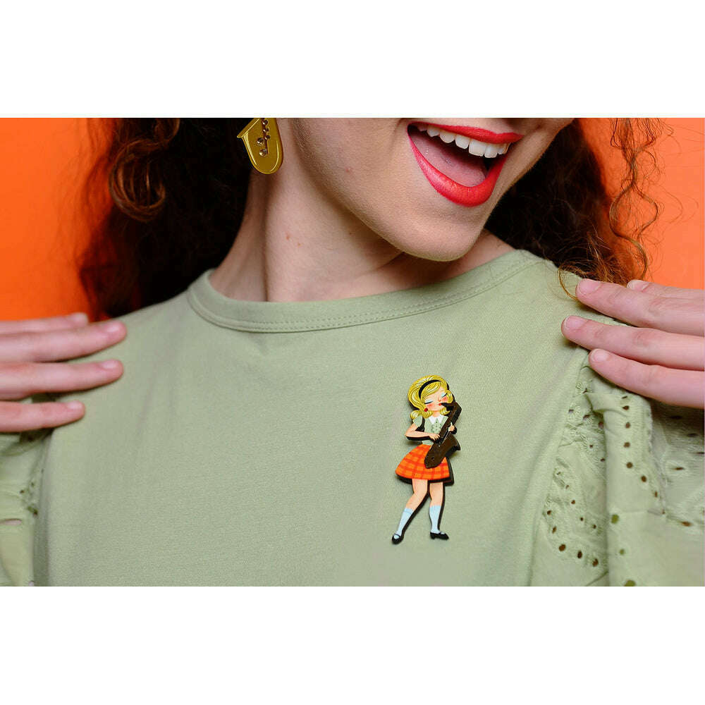 Saxophone girl brooch on mint green blouse, orange plaid skirt, red accents.