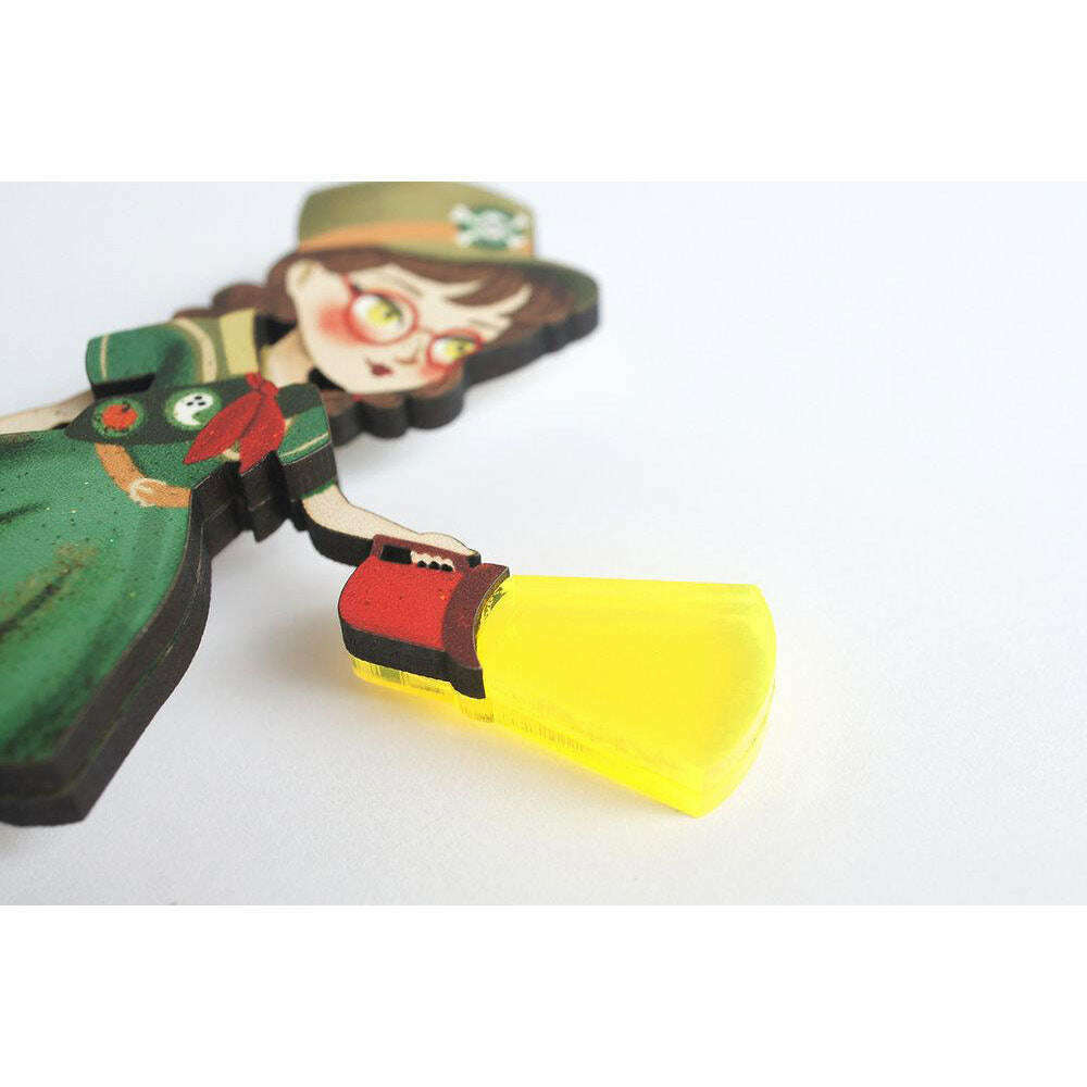 Girl Scout brooch close-up: cartoon scout girl in green dress holding yellow megaphone