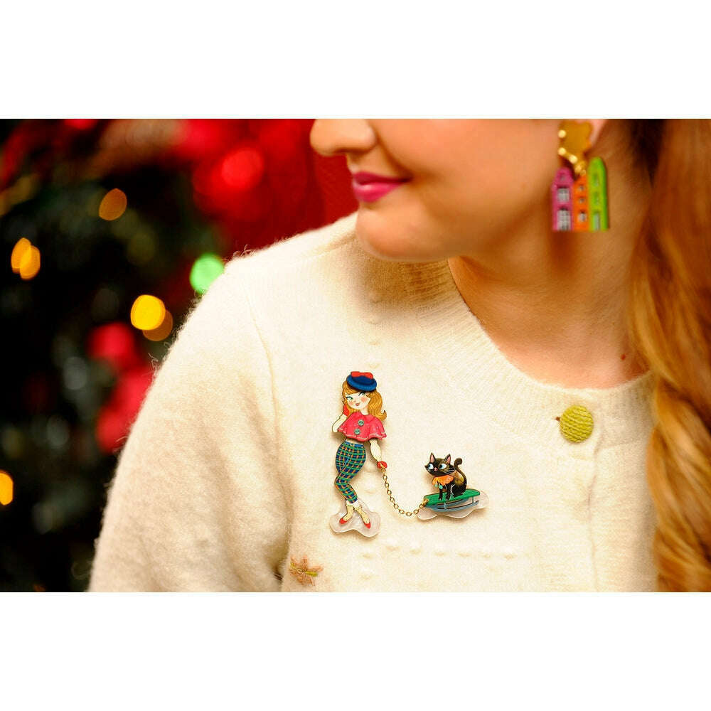Enamel girl and cat on sled brooch worn on cream sweater