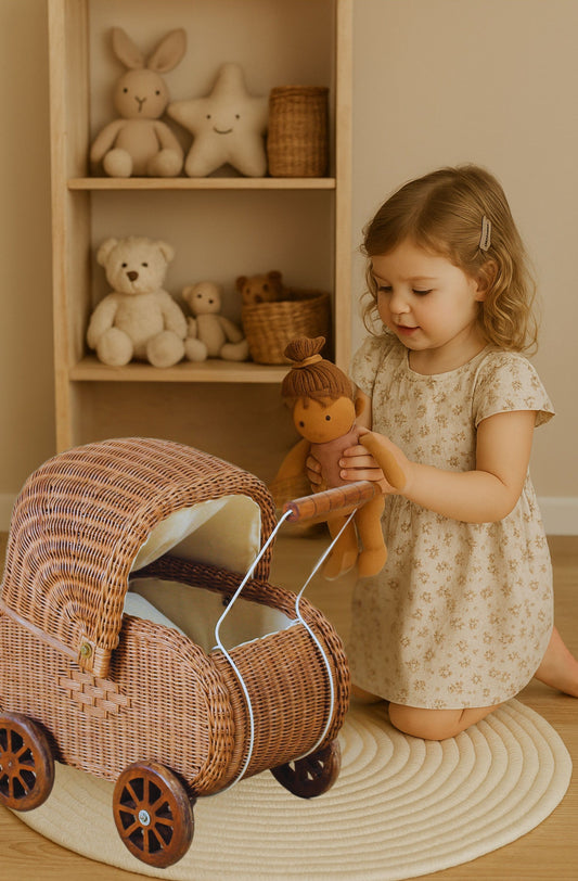 Brown rattan doll pram with a curved canopy and cream lining, shown beside a child