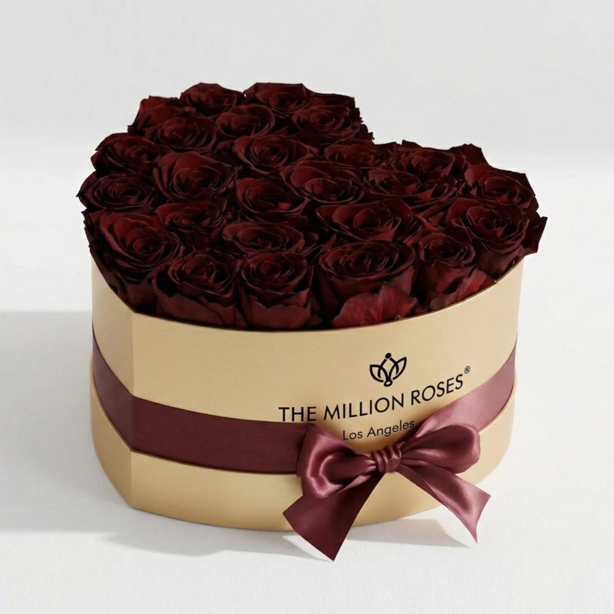 Gold gift box filled with burgundy roses, wrapped with satin ribbon bow