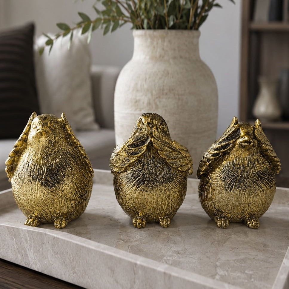 Gold-tone three bird figurines standing on a light stone display tray