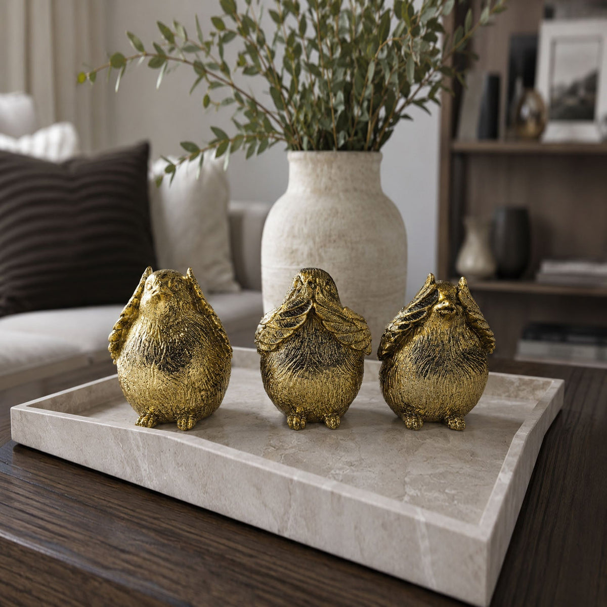 Gold-tone three bird figurines standing on a light stone display tray