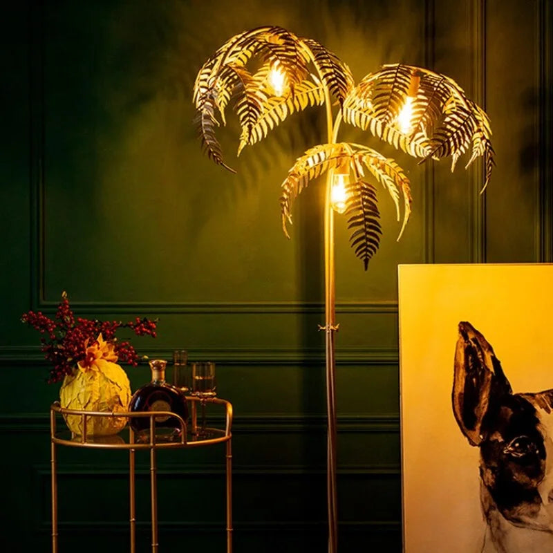 Gold palm tree floor lamp with three lit frond-shaped shades