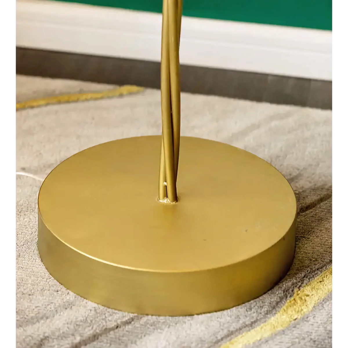 Close-up of the gold floor lamp's round metal base and stem