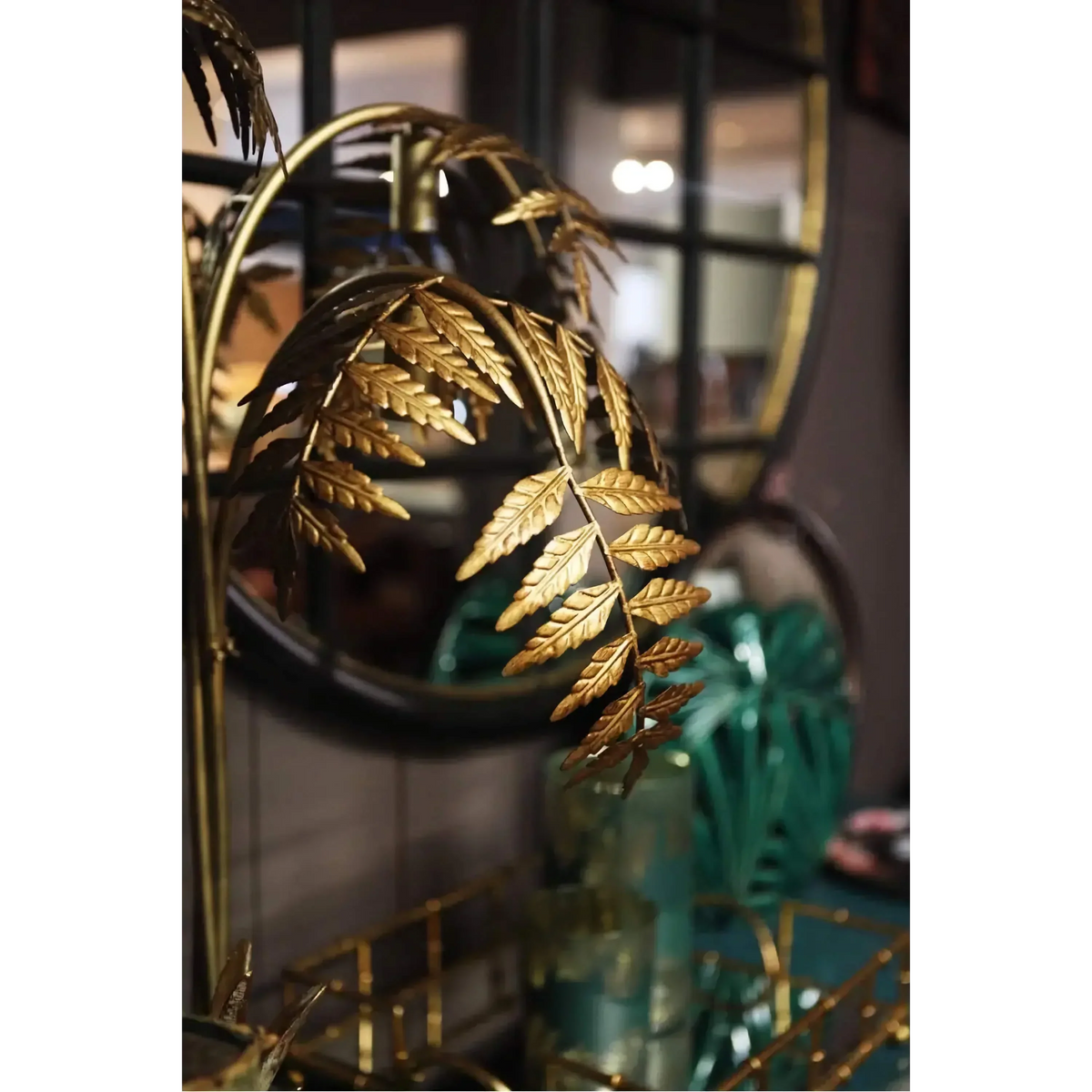 Gold metal palm frond details on a sculptural floor lamp