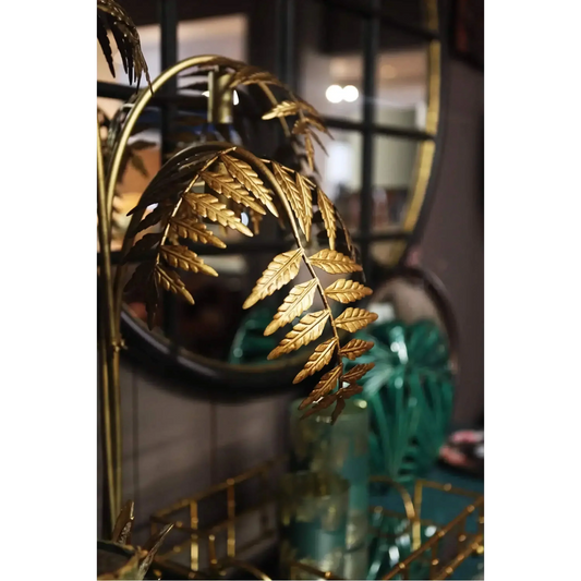 Gold metal palm frond details on a sculptural floor lamp