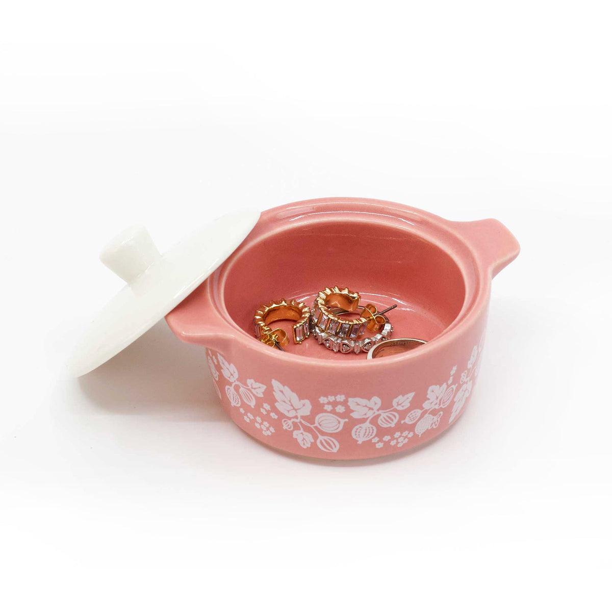 Pink ceramic casserole trinket box with lid off, showing gold-tone charm inside