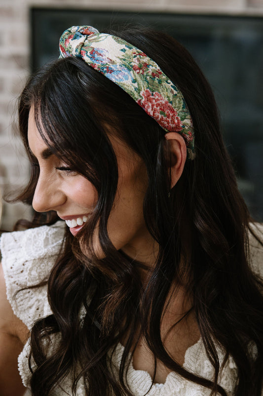 Floral knotted headband worn on dark hair, twisted knot at center
